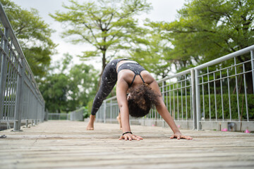 Fototapeta premium Portrait of Black African American woman in yoga class club doing exercise, runing or jogging at public garden park. Outdoor sport and recreation. People lifestyle activity with nature trees view.
