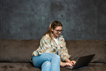 Young woman search the internet on laptop computer ads for selling and buying cars. Woman searches the internet in search of a safe reliable and affordable moving company.
