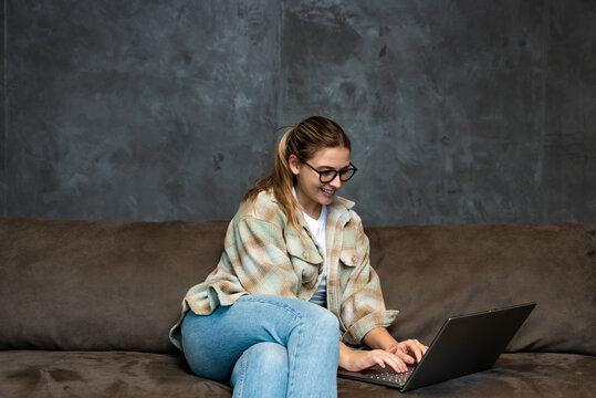 Young woman search the internet on laptop computer ads for selling and buying cars. Woman searches the internet in search of a safe reliable and affordable moving company.
