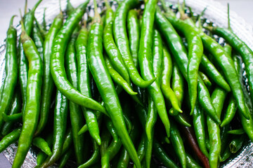 Collection of fresh green chilies on a plastic bowl.
