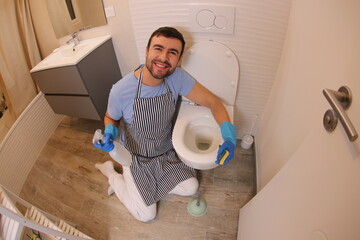 Cheerful man cleaning the toilet 