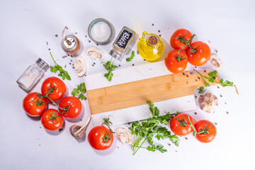 Cooking background with vegetable ingredients. Healthy dinner preparation flat lay, with fresh raw tomatoes, onion, garlic, herbs and greens, olive oil, salt, pepper seasonings, on white background 