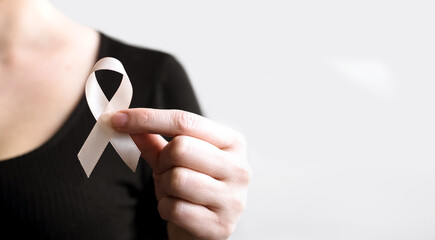 Woman's hands hold Peach Ribbon on beige background. Uterine Cancer Awareness month. Healthcare and...