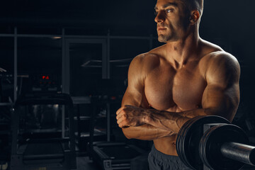 Fototapeta na wymiar Bodybuilder resting in the gym after weightlifting. Prepare training with dumbbells. 