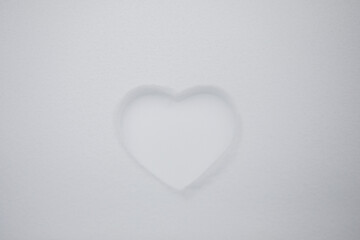 Heart shape on natural pure white soft snow surface in a cold weather day. Symbol of love in winter holiday season. Romantic outdoor concept for Valentine's day with copy space.