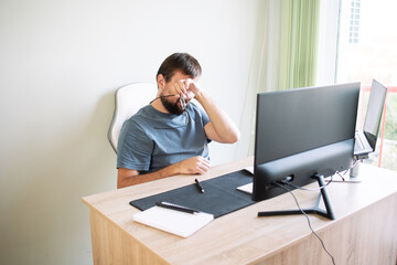 Office worker rubs his eyes after working at the computer. Concept: programmer, manager....