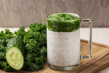 Chia seed pudding with curly kale, cucumber in glass on light wooden table. Healthy breakfast. Clean eating and superfoods concept.