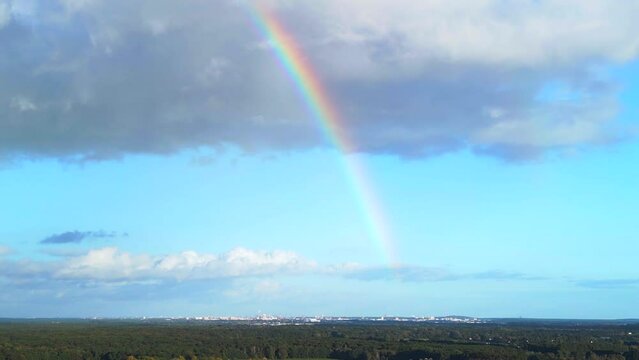 rainbow in blue sky, big cloud over small town. Perfect aerial view flight drone
