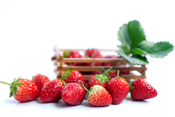 Fresh strawberries with green leaf, wooden basket with strawberries in blur background, isolated on white background