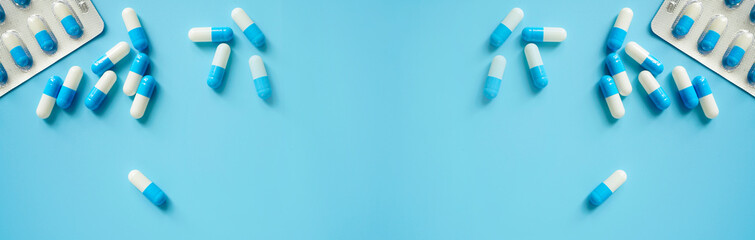 Blue-white antibiotic capsule pills and pill blister pack on blue background. Online pharmacy banner. World Health Day. Pharmaceutical industry. Prescription drugs. Antibiotic drug resistance concept. - obrazy, fototapety, plakaty