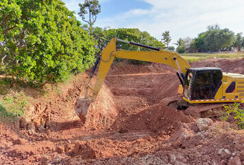 Backhoe bucket digging the soil at agriculture farm to make pond. Crawler excavator digging at...