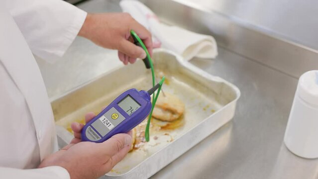 Chef probing meat with thermometer to check temperature is safe for eating