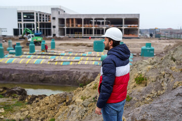 Engineer builder in a hard hat on the background of the construction of an industrial building