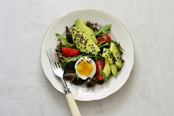 Avocado salad with olives, tomatoes, lettuce, arugula and boiled egg