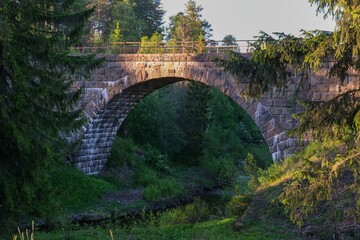old arch bridge made of stone in the forest