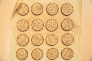 Freshly baked homemade sesame seed cookies on wooden board, rustic table. Healthy, tasty snack, honey seed bar, round form biscuits. Organic dessert, top view in row