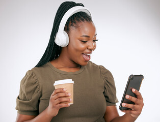 Music, coffee and surprise with a black woman in studio on a gray background listening to the radio. Phone, social media or headphones and a young female streaming an audio playlist with a drink