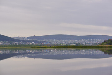 city surrounded by mountains on the lake. the city reflects on the water