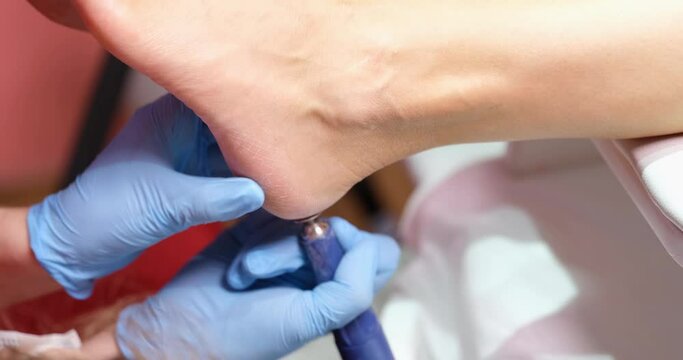 Manicurist using special grinding equipment to polish legs