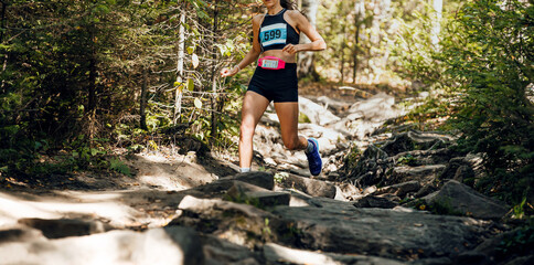 girl athlete running forest trail along stone