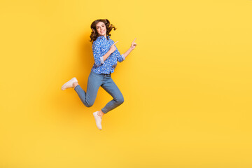 Fototapeta na wymiar Full body portrait of excited crazy lady jumping indicate fingers empty space isolated on yellow color background