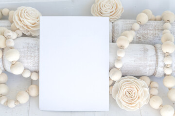Blank, white paper card invitation with wooden beads and flowers farmhouse styled mock-up