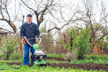 Farmer man plows the land with a cultivator preparing the soil for sowing