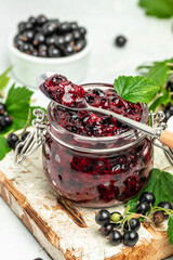 Black currant jam in a jar with fresh berry. Food recipe background. Close up