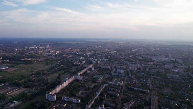 Aerial view of city panorama at sunset with residential neighborhoods and factory areas against a blurred skyline