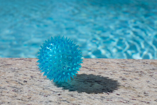 blue therapy massage ball, on the edge of a swimming pool, on a sunny day with concept of relaxation, vacations, spring brake