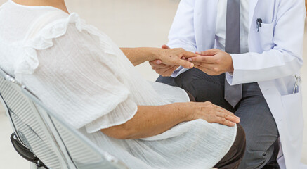 Young Asian doctor hands old woman patient talking about symptoms and treatment plan rehabilitation activities