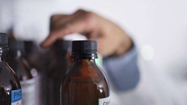 Doctor, hands and medicine for prescription, healthcare or cure for illness, disease or virus at pharmacy. Hand of medical professional choosing bottle medication on shelf for healthy medical results