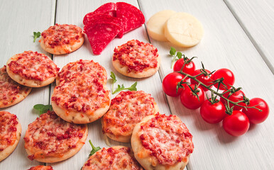 Mini pizzas, salami with mozzarella cheese, on a white table, top view, no people,