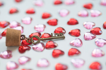 Glass bottle, key with the word love and heart shape gems on white background. Valentine's Day concept.