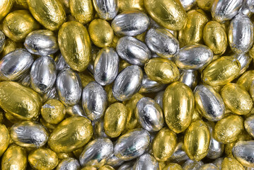 Large & small yellow, gold and silver foil wrapped chocolate easter eggs making a great background.