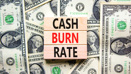 Cash burn rate symbol. Concept words Cash burn rate on wooden blocks on a beautiful background from dollar bills. Business cash burn rate concept. Copy space.