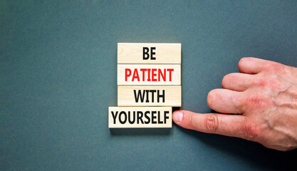 Patient with yourself symbol. Concept words Be patient with yourself on wooden blocks. Beautiful grey table grey background. Businessman hand. Business patient with yourself concept. Copy space.