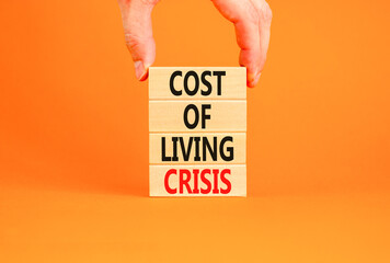 Cost of living crisis symbol. Concept words Cost of living crisis on wooden blocks. Beautiful orange table orange background. Businessman hand. Business cost of living crisis concept. Copy space.