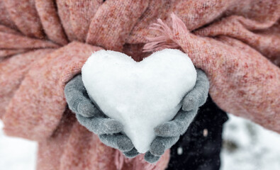 Close-Up of Female Hands Holding a Snow Heart with a Pink Scarf on a Winter Day