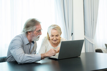 Senior couple working and checking personal finances with laptop at home.
