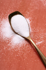 spoon with sugar on color background orange gold spoon