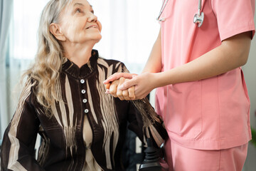 Nurse standing beside senior woman and holding hands to encourage woman to cure from disease in living room,Medical care for the senior at home concept.
