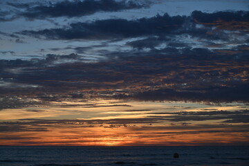 sunset under the clouds by the sea