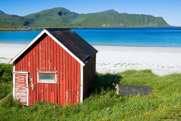 Traditional red wooden hut by Ramberg beach, Lofoten, Norway