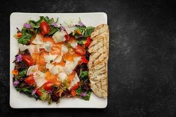 Salmon carpaccio with cheese, tomatoes, and crouton, on a plate