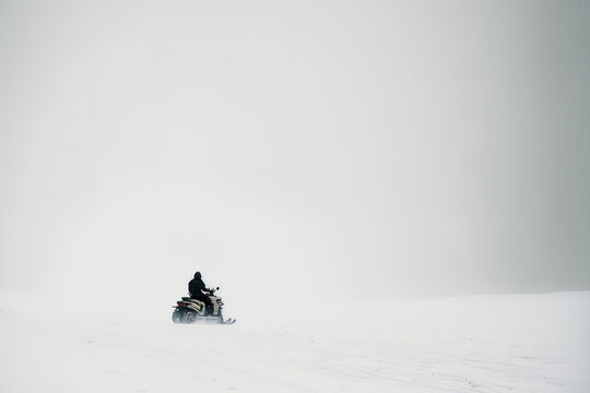 Persona no reconocible utilizando una moto de nieve en un paisaje nevado.  Imagen generada con AI