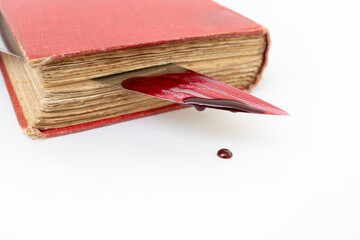 Bloody knife between a vintage book pages, with dripping red paint