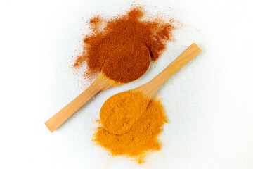 two wooden spoon with curcuma and smoked paprika on white