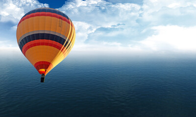 Hot air baloon is flying over the ocean