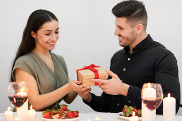 Happy young couple in love celebrating Valentines day, exchanging gifts